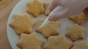 Pastry chef or baker adds sugar icing or glazing on top of homemade ginger or butter cookies shaped like stars. Baking for family, simple recipes for homemade food and desserts - Powered by Shutterstock - Get 15% off with code: PIKWIZARD15