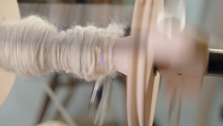Close up: Spinning wheel bobbin collects wool yarn in modern craft