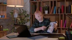Successful determined bearded mature businessman making video call online using laptop , discussing financial data and charts with colleagues while working from home office at night, - Powered by Shutterstock - Get 15% off with code: PIKWIZARD15
