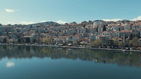 Drone flying aside a village on a green hill in Europe, red roof tops, sunny weather, blue water lake, Greece 4K video