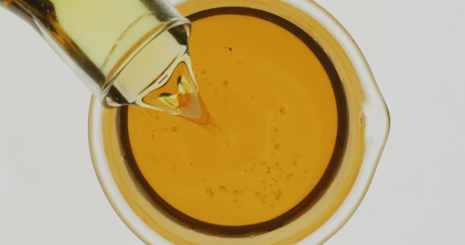 Scientist chemist pouring engine oil from glass into beaker., Top view
