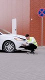 Following car accident male inspector evaluates vehicle damage aftermath of incident vertical video. Automobile collision man inspector inspector assess car damage impact of accident.