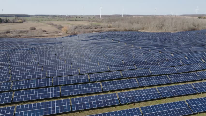 Vast solar panel field under a clear sky with wind turbines in the background, expansive green landscape - Powered by Shutterstock - Get 15% off with code: PIKWIZARD15