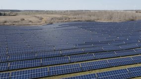 Vast solar panel field under a clear sky with wind turbines in the background, expansive green landscape - Powered by Shutterstock - Get 15% off with code: PIKWIZARD15