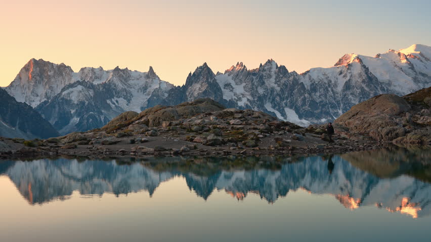 Landscape of Lac Blanc with Mont Blanc massif and male traveler walking reflect on the lake among French Alps in the morning at Chamonix Mont Blanc, Haute Savoie, France