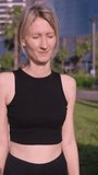 Young girl in black top runs in tropical park with palm trees on sunny warm day. concept of wellness workout woman fitness sunrise jogger. In modern park among palm trees. Vertical video