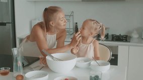 Loving cheerful mother and little daughter having fun while cooking pastries, sprinkling sugar powder, laughing feel happy, fooling around standing in cozy kitchen. Family pastime - Powered by Shutterstock - Get 15% off with code: PIKWIZARD15