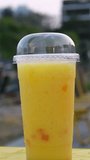 Street food in a plastic glass served Mango drink with syrup Mixing mango smoothie in a glass with fresh mango