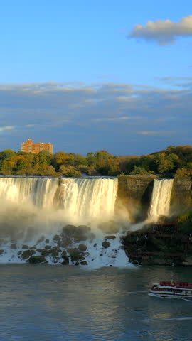 Niagara Falls - American Falls and Bridal Veil Falls with a rainbow in the sunset rays of the setting sun. View from Canadian Side. Vertical video.