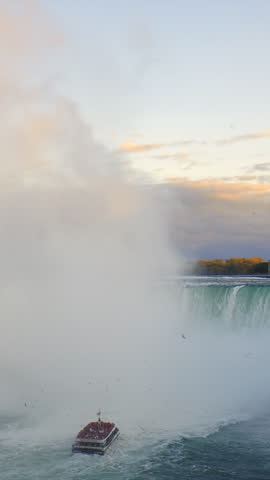 Niagara Falls - American Falls and Bridal Veil Falls with a rainbow in the sunset rays of the setting sun. View from Canadian Side. Vertical video.
