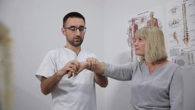 Doctor examines womans wrist, arm, and elbow in a medical consultation video