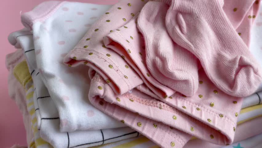 Stack of Baby bodysuits. Baby crocketed toy of dog next to a stack rompers for kids 