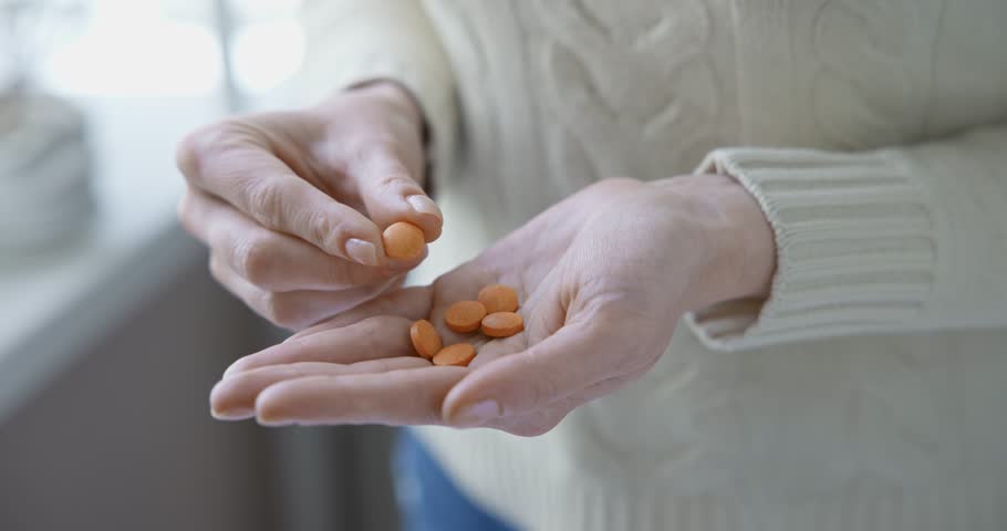 pharmacy and treatment concept - close up view of Caucasian woman holding Vitamin C tablets in her palm