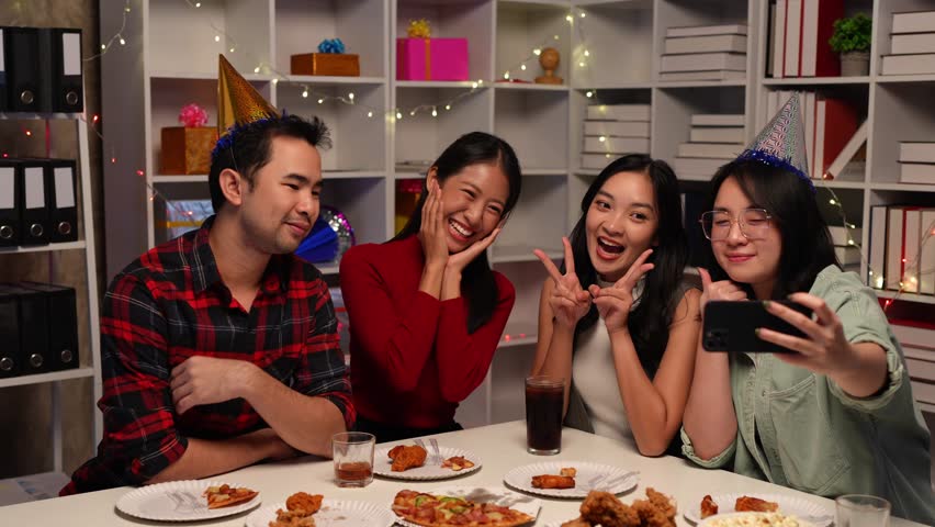 Group of Asian male and female friends having fun and celebrating a fast food feast with soft drinks on the table during a happy friends gathering party and smiling, cheerful, delicious weekend.