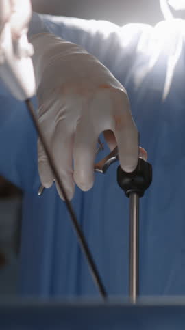 Close up of male medics using modern equipment during surgery. Professional surgeons in uniform operate patient in hospital using laparoscopy instruments. Medical staff at work in operating room.