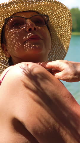 Elderly man taking picture of attractive senior woman with vintage camera on the beach. Funny active loving elderly couple carefree and happy together on vacation in Northern Europe, Finland