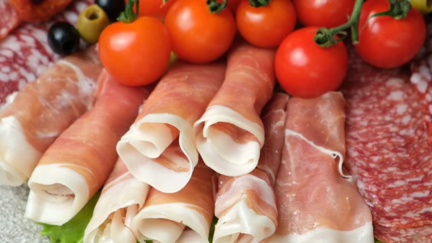 Meat platter - ham, salami and other types of meat delicacies with olives and tomatoes