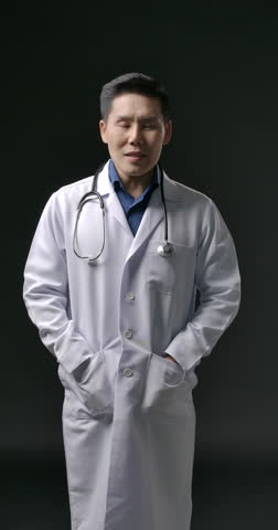 POV of young handsome asian male doctor in lab coat listening and talking to camera with smile on vertical screen. Telehealth Telemedicine concept. Therapist make online video call consult patient.