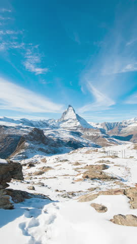 Panoramic nature landscape timelapse of Mount Matterhorn covering with white snow and clouds movement on mountains peak in a sunny day at Zermatt, Switzerland. Famous travel ski resort in Swiss alps.