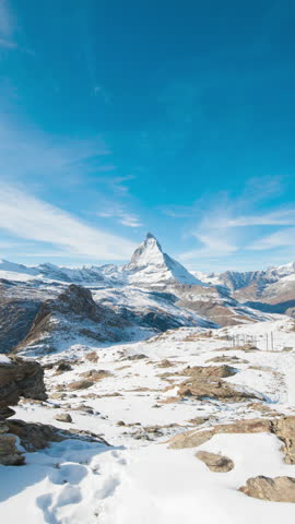 Panoramic nature landscape timelapse of Mount Matterhorn covering with white snow and clouds movement on mountains peak in a sunny day at Zermatt, Switzerland. Famous travel ski resort in Swiss alps.