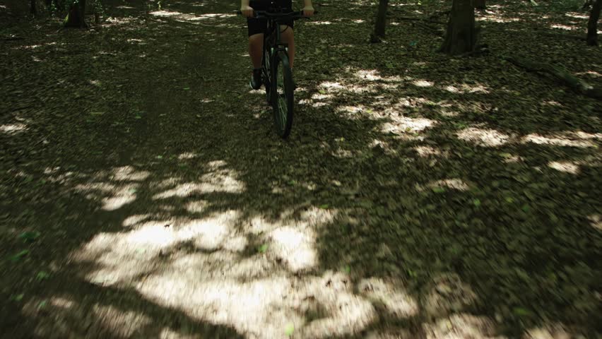 Unsportsmanlike overweight cyclist riding through forest. Weight loss training. Off-road trail riding, adult man with hardtail mountain bike.
