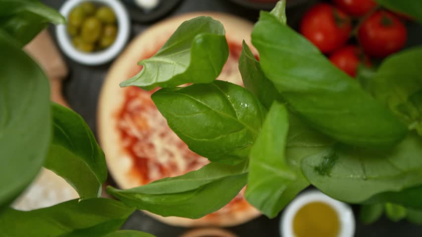 Super Slow Motion of Falling Basil Leaves on Pizza Dough. Filmed on High Speed Cinema Camera, 1000fps, Placed on High Speed Cine Bot. Camera in Motion, Following Objects.