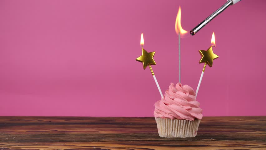 Birthday cupcake. Happy birthday. pink cupcake with candles and sparkler on a wooden table and pink background. Copy space. place for text.