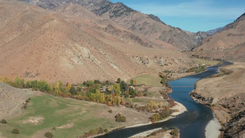 Drone footage of a remote landing strip, bridge over a river, and camp surrounded by mouintains and a river in the Frank Church River of No Return Wilderness in Idaho