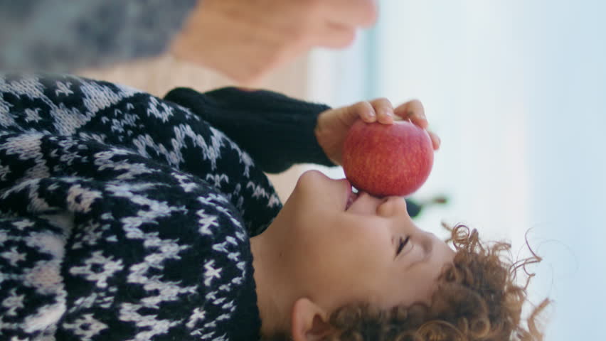 Little boy resting picnic at autumn beach closeup. Cheerful kid having fun eat fruits together with unknown mother vertical oriented. Happy carefree child enjoy seashore vacation. Childhood memories.