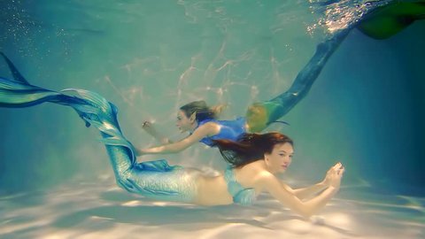 Couple of happy mermaids swims.