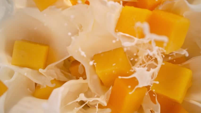 Super Slow Motion Shot of Mango Cuts Followed by Camera Falling into Milk at 1000fps.
