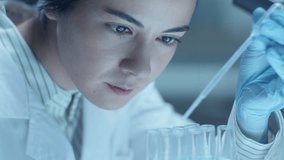Female medical microbiologist in gloves pouring liquid chemicals in test tubes with pipette while performing test in laboratory. Close-up view, rack focus - Powered by Shutterstock - Get 15% off with code: PIKWIZARD15