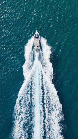 Vertical Screen: This Image Captures A Motorboat Cruising Through Vibrant Blue Waters, Its Foamy Wake Creating A Beautiful Contrast Against The Deep Blue. 
