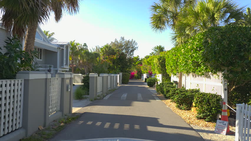 Car point of view driving on scenic road in sunny Florida. Casey Key coastal residential community picturesque streets.