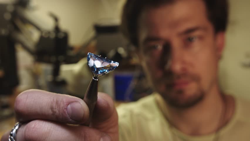 A man is holding a blue gemstone in their hand