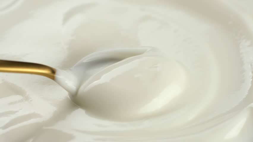 Greek yogurt or sour cream stirring with spoon, close up