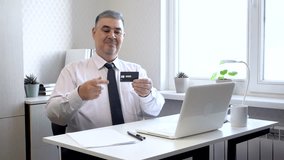 A man in a tie sits at a table, shows a bank card and gives a thumbs up. Suitable for advertising banking services, cards and terms of service. - Powered by Shutterstock - Get 15% off with code: PIKWIZARD15