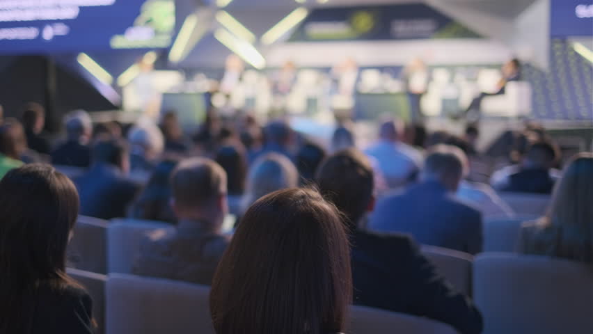 An audience of engaged professionals listens intently at a conference presentation, capturing the essence of business learning and networking in a corporate environment.
