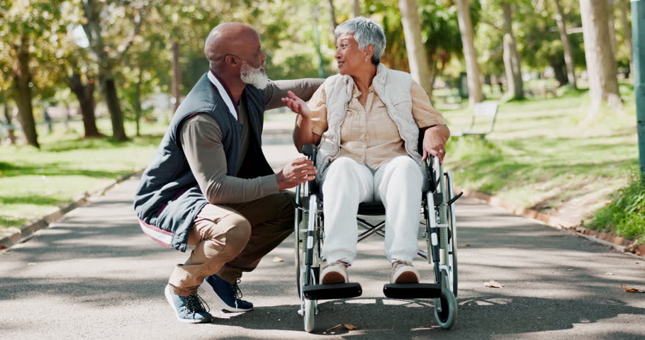 Park, old man and senior woman in wheelchair, nature and conversation with support, love and marriage. Outdoor, couple and person with disability, summer and relationship with trees, care and talking