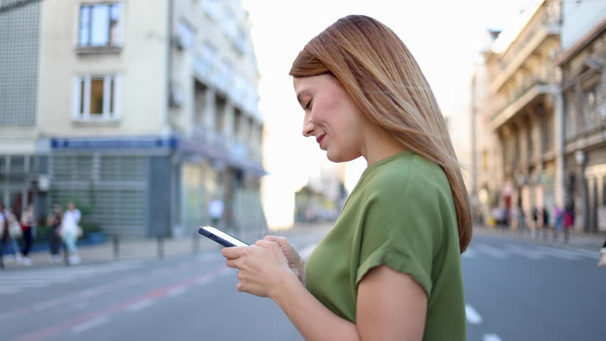 eautiful, young woman walking through the city and using smartphone