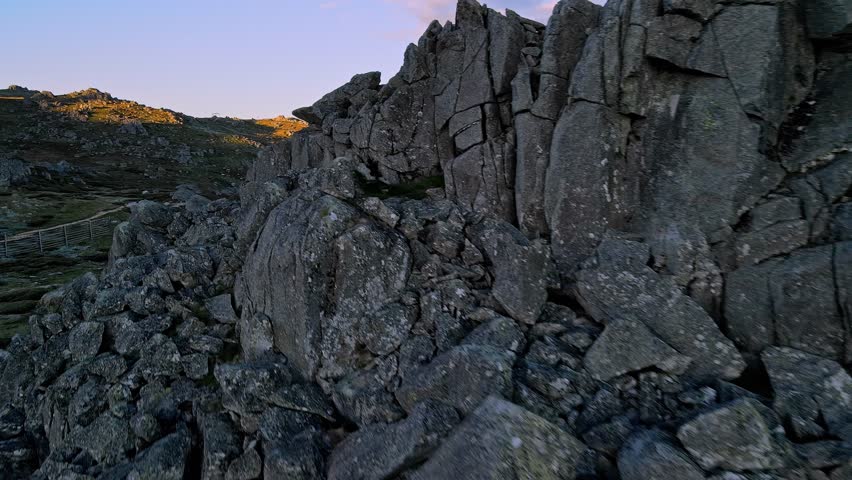 Aerial reveal of Snowy Mountains vista in summer from behind rocky outcrop, New South Wales, Australia
