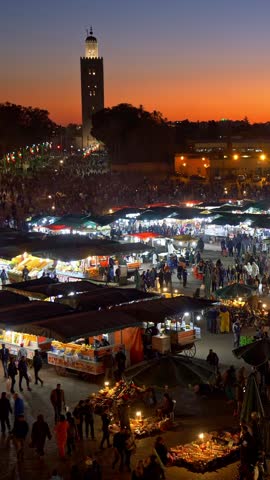 Crowds of people on Jemaa el-Fnaa marketplace of Marrakesh, Morocco just after sunset. Many counters with various goods. Marrakesh, Morocco. Vertical shot