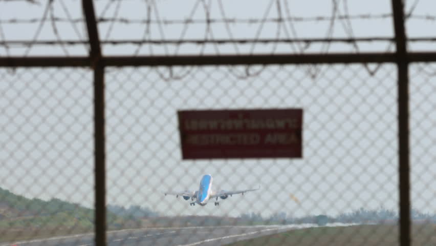Long shot of commercial plane taking off at Phuket airport. Passenger aircraft climbing, rear view