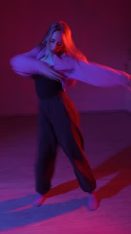 A young woman dances contemporary dances in blue and red light. Long exposure. Slow motion Vertical video. 