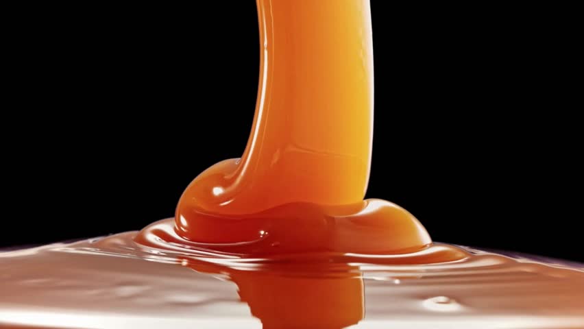 Super Slow Motion Shot of Rippling Melted Caramel Super Slow Motion Shot of Salted Caramel Explosion Towards Camera Isolated on Black Dripping caramel drops of sweet caramel sauce. 