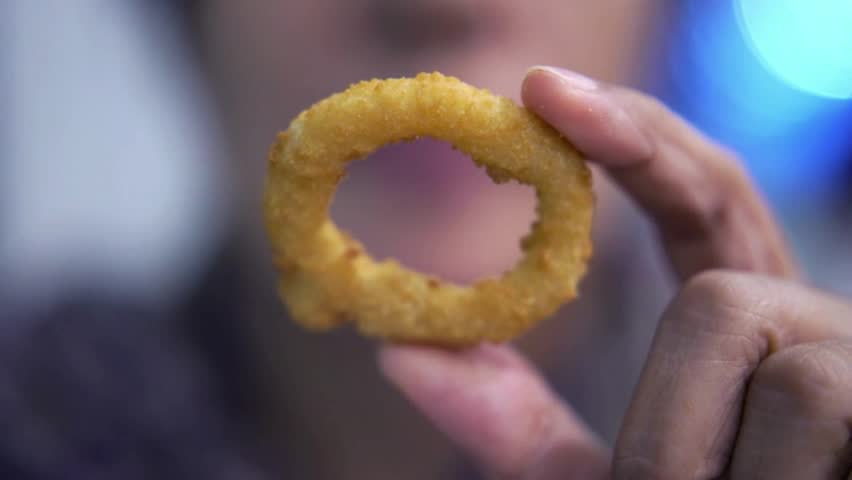 The cook fries the onion rings in boiling oil. Fried  rings, crispy , 4k. Boiling oil, deep-fried  rings , rotation in circle. Fast food Turning, top view. selective focus .Roasted 