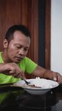 Vertical video close-up of Asian Indonesian man is eating chicken satay.
Satay is a traditional food from Surabaya, East Java.
