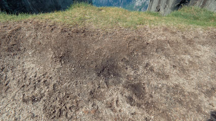 Norway. Tourist approaches the edge of the cliff. Great magnificent nature of the Norwegian Fjord. Top view of beautiful landmark. Scandinavian nature clean lake and blue sky, around the mountain
