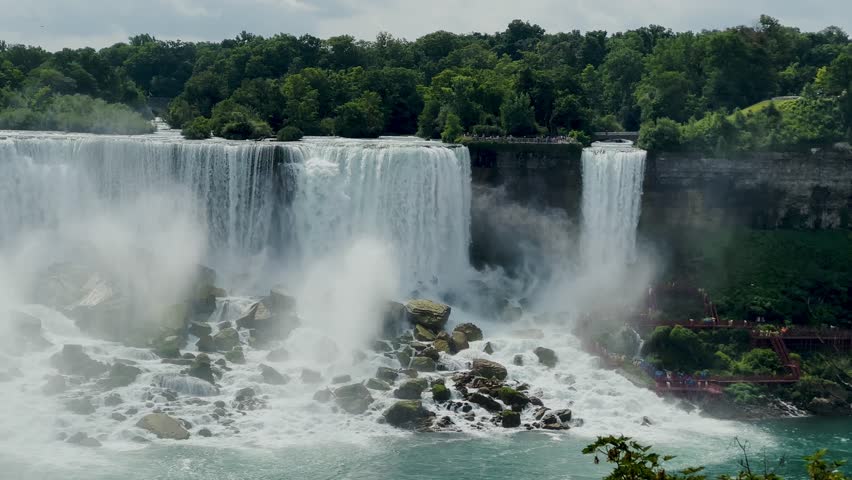 Niagara Falls on both the American and Canadian sides. Powerful waterfall of crystal clear waters. Majestic and misty rapids of the 56 km long Niagara River. Boat under the waterfalls with tourists.
