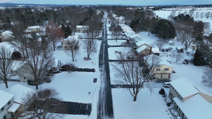 Winter in American neighborhood. Aerial rising shot above quaint two story houses in USA suburb with snow.